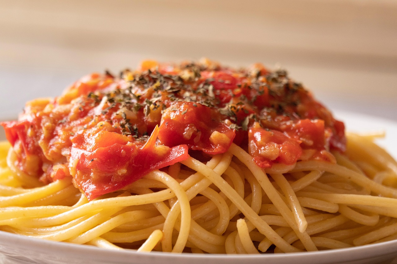 Piatto di pasta al pomodoro con basilico fresco e sugo ricco, pronto da gustare.